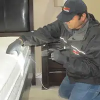 Bed bug inspection technician checking a mattress and bed frame for signs of infestation in Sarasota, FL