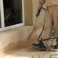 General pest control technician spraying exterior perimeter around a home in Sarasota, FL