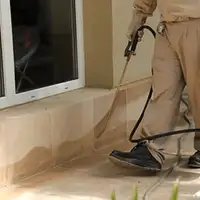 General pest control technician spraying exterior perimeter around a home in Sarasota, FL