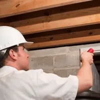 Termite inspection technician checking a basement wall and framing for termite activity in Sarasota, FL