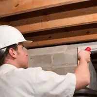 Termite inspection technician checking a basement wall and framing for termite activity in Sarasota, FL
